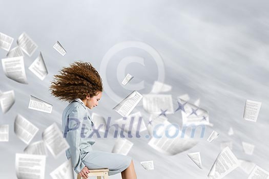 Young tired businesswoman with waving hair among flying documents