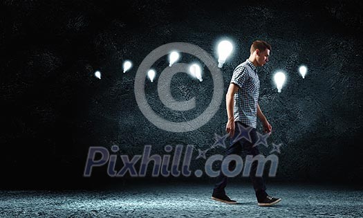Young man and electrical bulb against dark background Young man and electrical bulb against dark background