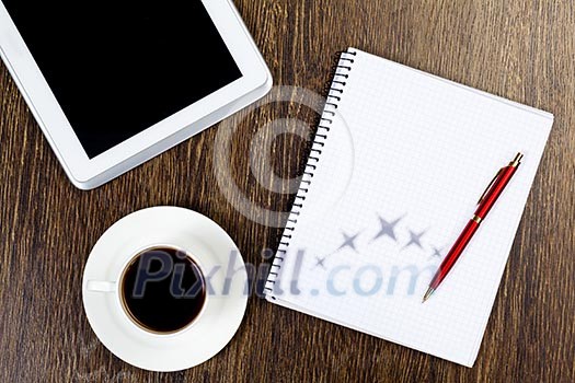 Tablet pc cup of coffee and notepad at table