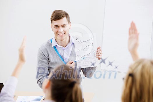 Young teacher in classroom standing in front of class Young teacher in classroom standing in front of class