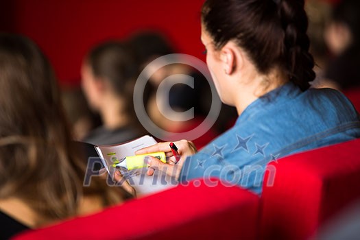 Female university student sitting in class, taking notes