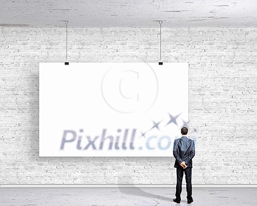 Image of businessman standing with back and looking at white banner Image of businessman standing with back and looking at white banner