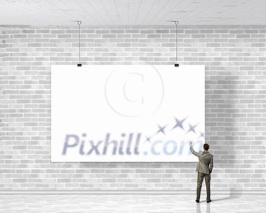 Image of businessman standing with back and writing on blank banner Image of businessman standing with back and writing on blank banner