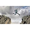 Young businessman jumping over mountain gap. Risking in business