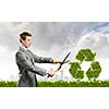 Young businessman cutting bush in shape of recycle symbol