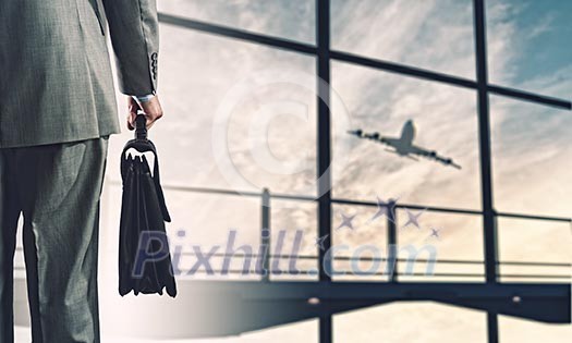 Back view of businessman holding suitcase with airplane at background