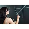 Pretty, young college student drawing on the chalkboard/blackboard during a math class (shallow DOF; color toned image)