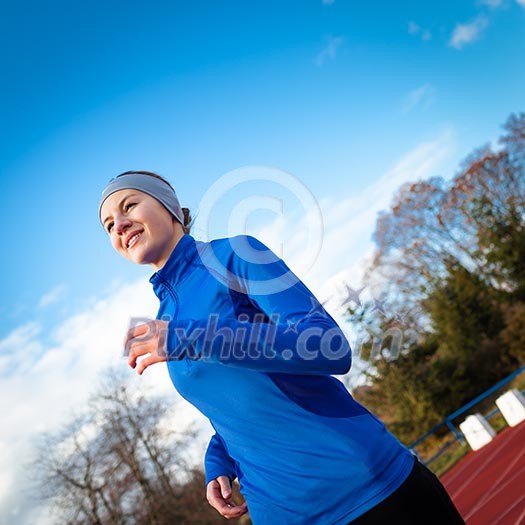 Young woman running at a track and field stadium