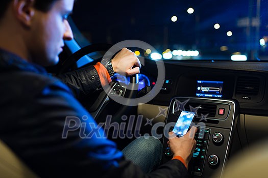 Driving a car at night -man driving his modern car at night in a city (shallow DOF; color toned image)