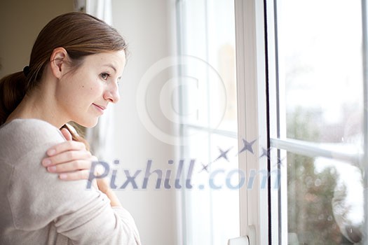 Woman lookong from a window of her house on a cold and snowy winter day Woman lookong from a window of her house on a cold and snowy winter day