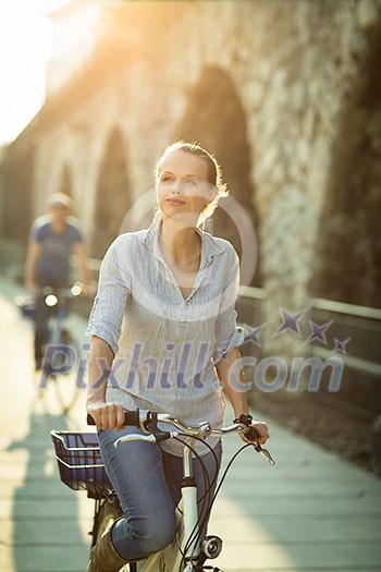 Pretty, young woman riding a bicycle in a city with her boyfriend (color toned image; shallow DOF) Pretty, young woman riding a bicycle in a city with her boyfriend (color toned image; shallow DOF)