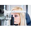 Optometry concept - pretty, young female patient having her eyes examined by an eye doctor (color toned image; shallow DOF)