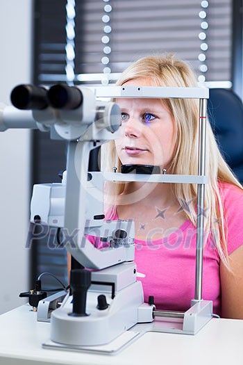 Optometry concept - pretty, young female patient having her eyes examined by an eye doctor (color toned image; shallow DOF) Optometry concept - pretty, young female patient having her eyes examined by an eye doctor (color toned image; shallow DOF)