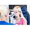 Optometry concept - pretty, young female patient having her eyes examined by an eye doctor (color toned image; shallow DOF)