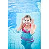 Portrait of a young woman relaxing in a swimming pool (shallow DOF; color toned image)