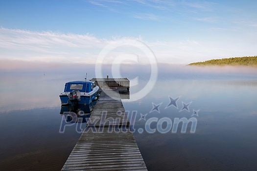 Blue boat by a wooden pier on a misty morning