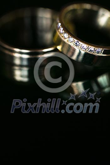 Wedding day details - two lovely golden wedding rings awaiting their moment, with some nice reflections Wedding day details - two lovely golden wedding rings awaiting their moment, with some nice reflections