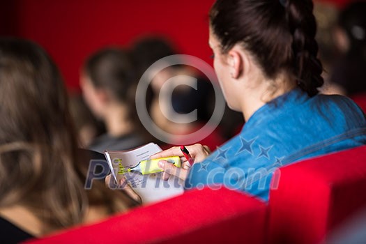 Female university student sitting in class, taking notes