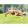 Young attractive sport girl in park doing push ups