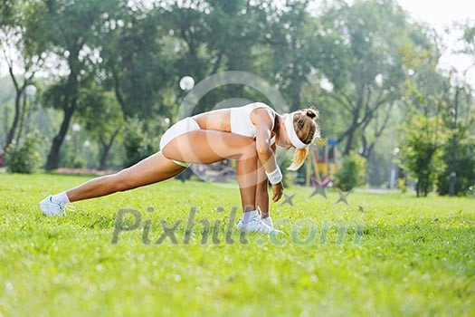 Young sport woman in white stretching in park