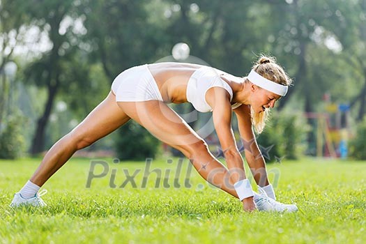 Young sport woman in white stretching in park