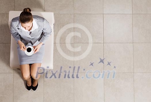 Top view of busineswoman sitting on chair with cup of coffee Top view of busineswoman sitting on chair with cup of coffee