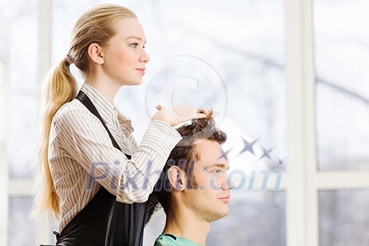 Young man in chair at barbers and woman hairdresser
