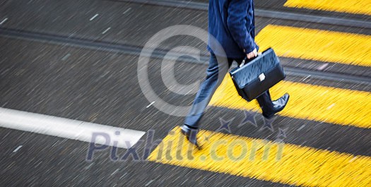 Man rushing over a road crossing in a city on a rainy day (motion blurred image)