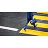 Man rushing over a road crossing in a city on a rainy day (motion blurred image)