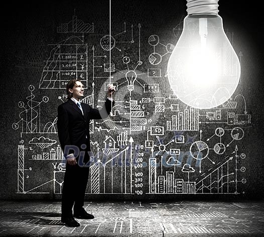 Businessman switching on light bulb with business sketches at background