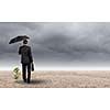 Rear view of businessman with umbrella protecting sprout