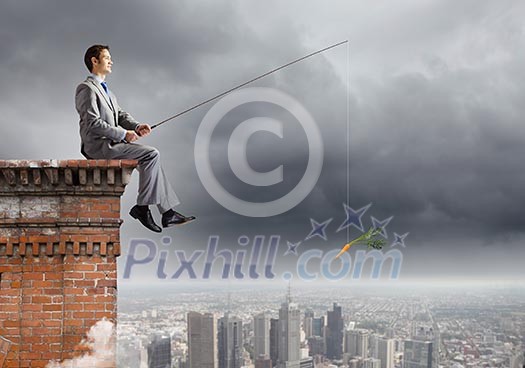 Businessman sitting on top of building and fishing with rod