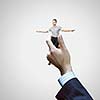 Young businesswoman in miniature in hand of businessman