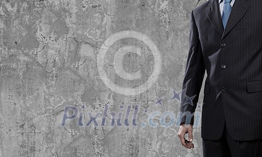 Close up of businessman body in suit against cement background