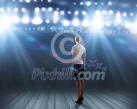 Rear view of businesswoman standing in lights of stage Rear view of businesswoman standing in lights of stage