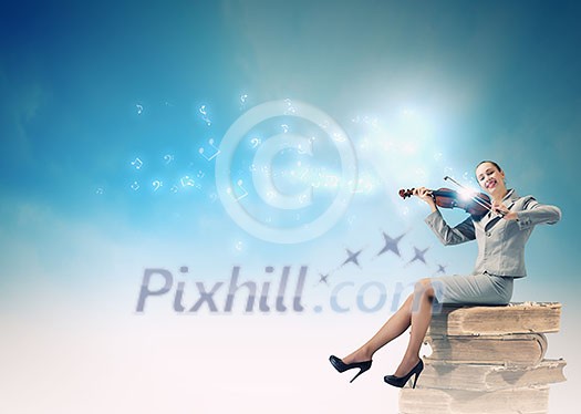 Young businesswoman sitting on pile of books and playing violin