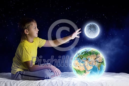 Cute boy sitting in bed holding Earth planet. Elements of this image are furnished by NASA