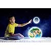 Cute boy sitting in bed holding Earth planet. Elements of this image are furnished by NASA