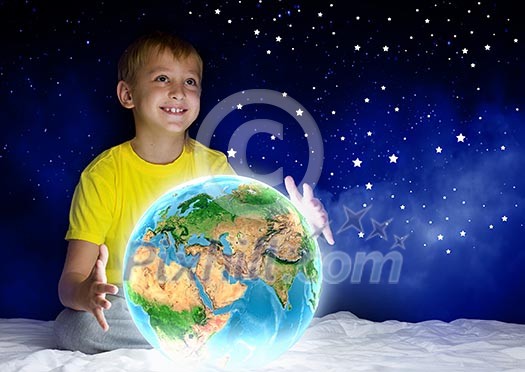Cute boy sitting in bed holding Earth planet. Elements of this image are furnished by NASA