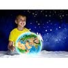 Cute boy sitting in bed holding Earth planet. Elements of this image are furnished by NASA