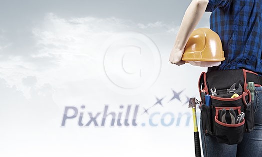 Close up of woman mechanic with yellow helmet in hand against city background