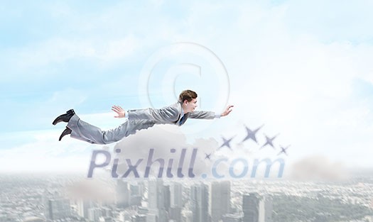 Young super businessman flying high in sky Young super businessman flying high in sky