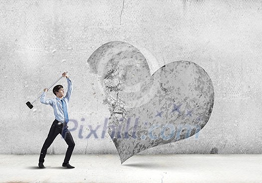 Aggressive businessman breaking stone heart with hammer