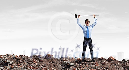 Young determined businessman with hammer in hands