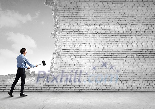 Young determined businessman with hammer in hands