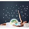 Cute girl sleeping in bed and looking at Earth planet. Elements of this image are furnished by NASA