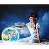 Cute girl sitting in bed and looking at Earth planet. Elements of this image are furnished by NASA