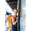 Pretty, young woman in a trainstation, waiting for her train, boarding a train (color toned image)