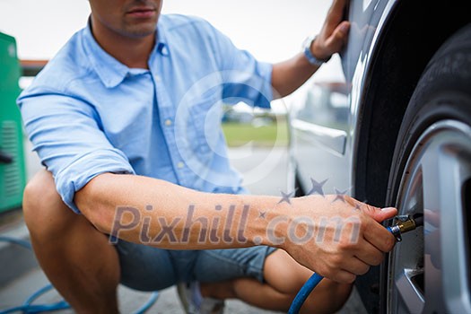 Driver checking air pressure and filling air in the tires of his modern car