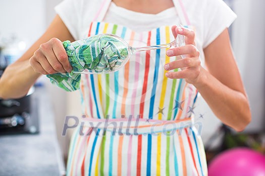 Young woman polishing a glass in her modern kitchen